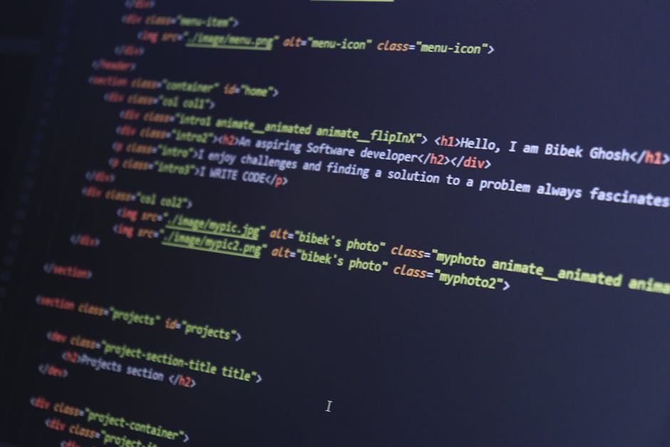 A cluttered desk workspace featuring a black computer monitor displaying lines of code in colorful syntax highlighting. The monitor is centrally positioned on the dark desk surface, surrounded by diso